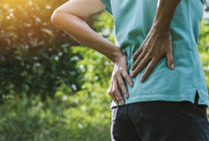 Woman grasping back after gardening due to sciatica pain flare up
